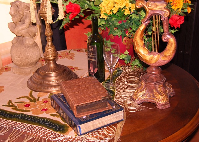 Books on table with flowers, wine bottle and glass.